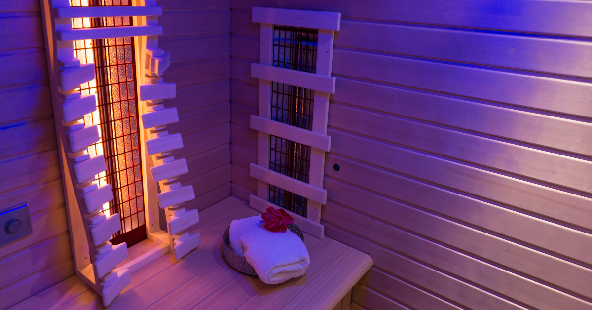Infrared sauna interior with a folded towel and flower on a wooden bench.