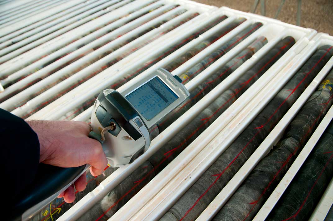 Hand scanning core samples using a handheld device in a lab setting.