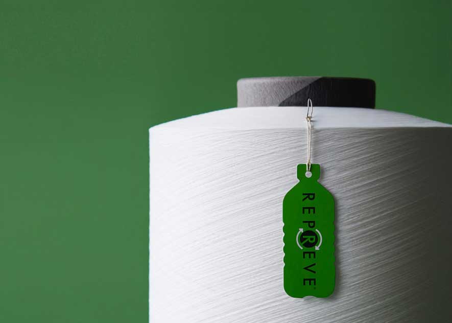 Close-up of white thread spool with a green tag with the REPREVE logo