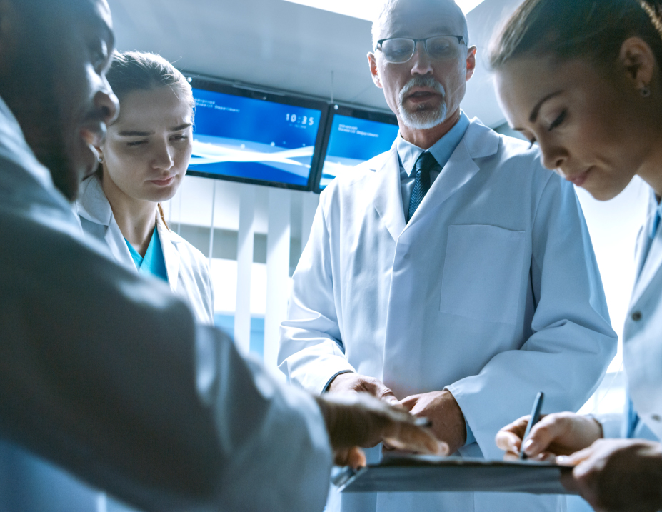 Group of scientists in lab coats discussing a project in a bright laboratory.