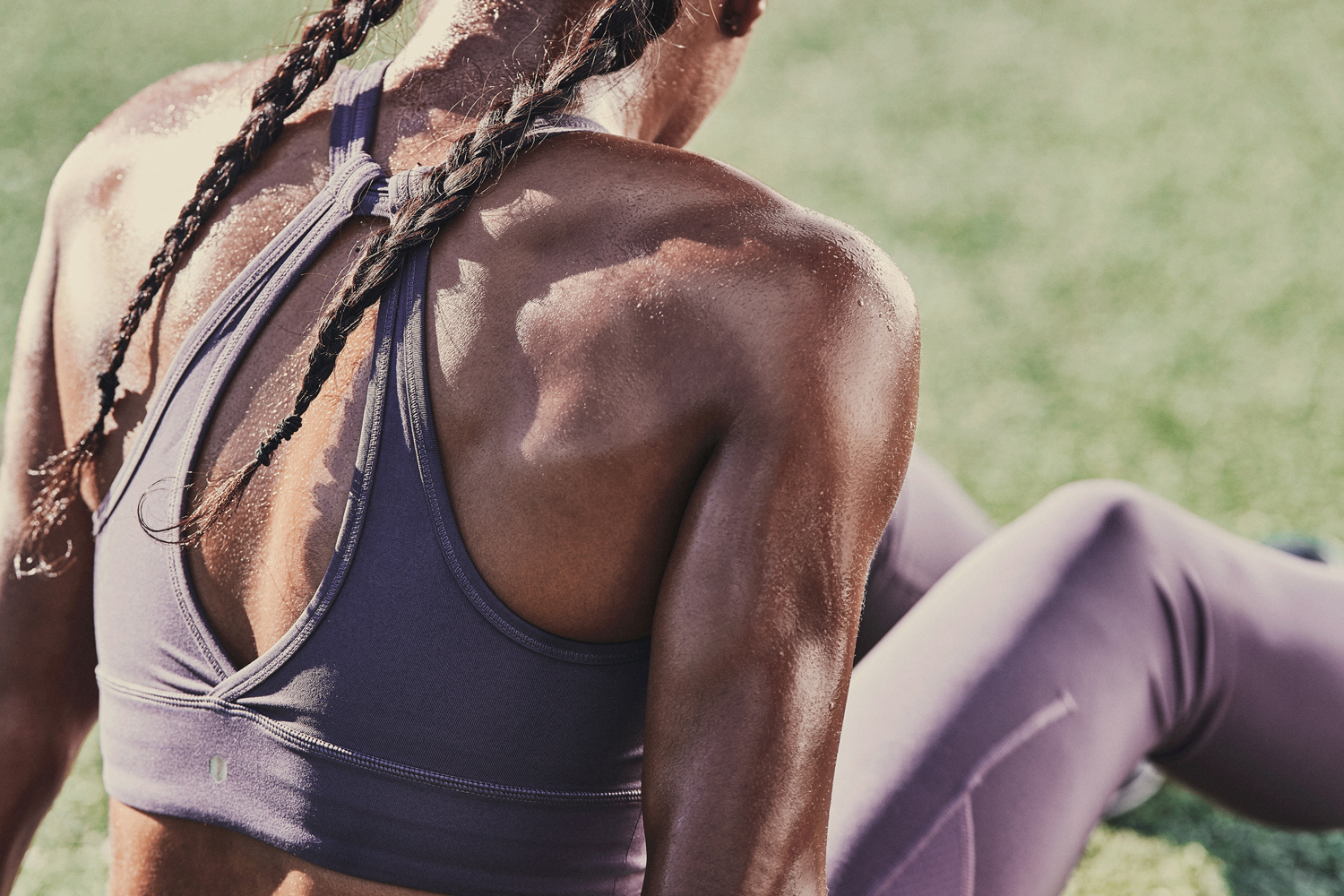 A muscular woman wearing a sports bra made with Celliant material, as sweat and sunlight glistens on her back