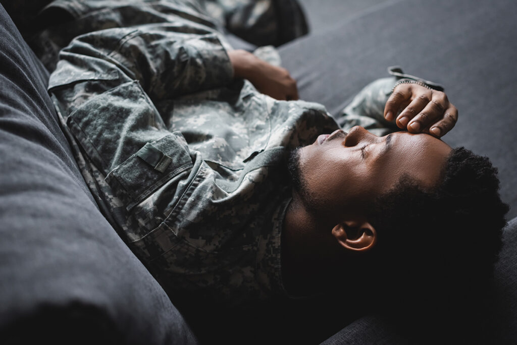 A soldier wearing their military fatigues uniform takes a well deserved nap.