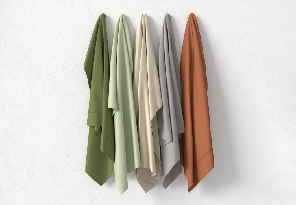 Five hanging fabric swatches or blankets in an earth-tone color palette, arranged from left to right: dark olive green, sage green, beige, gray, and terracotta brown.