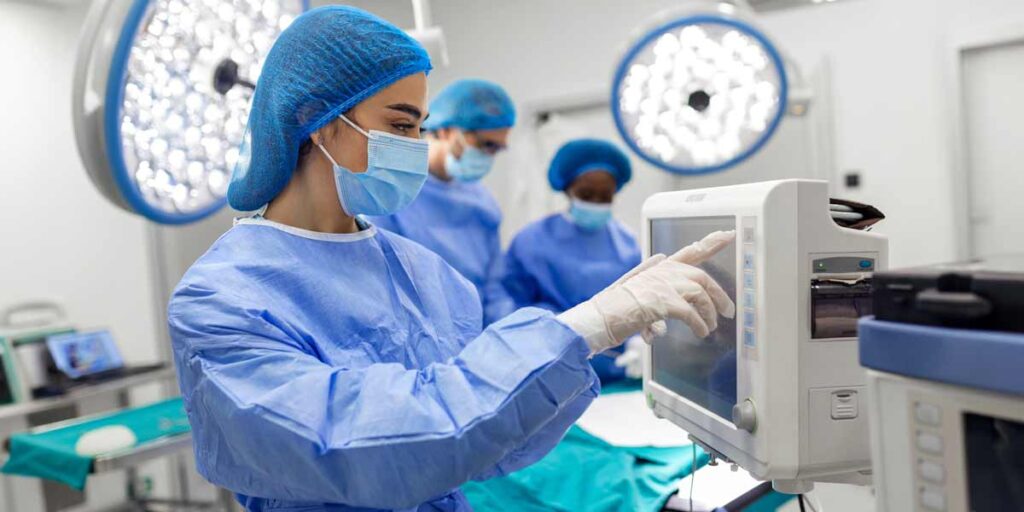 Surgical team in an operating room, with a nurse adjusting medical equipment.