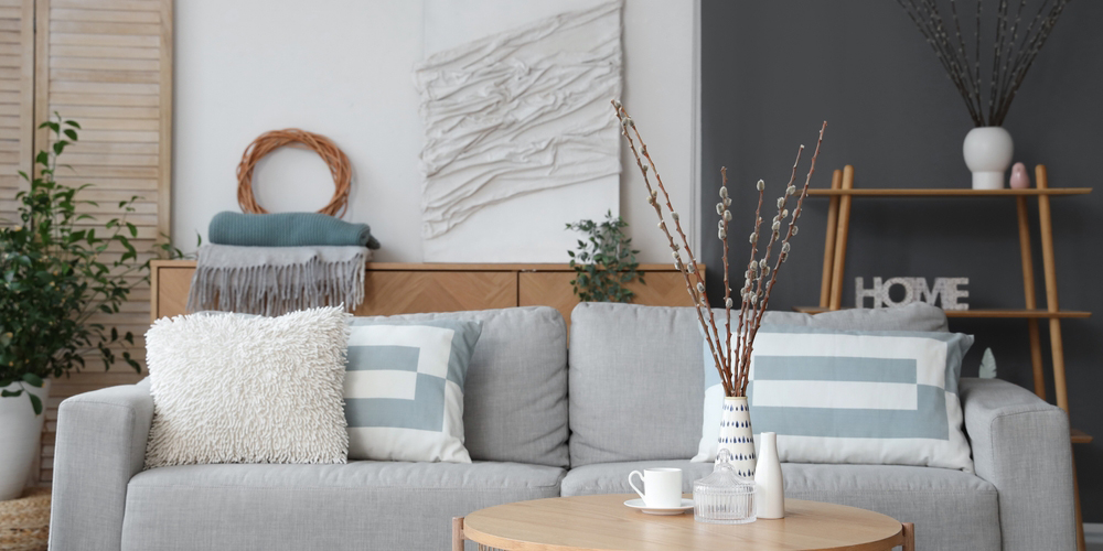 A contemporary living room with a light gray sofa, striped and textured pillows, and a coffee table with decorative vases.