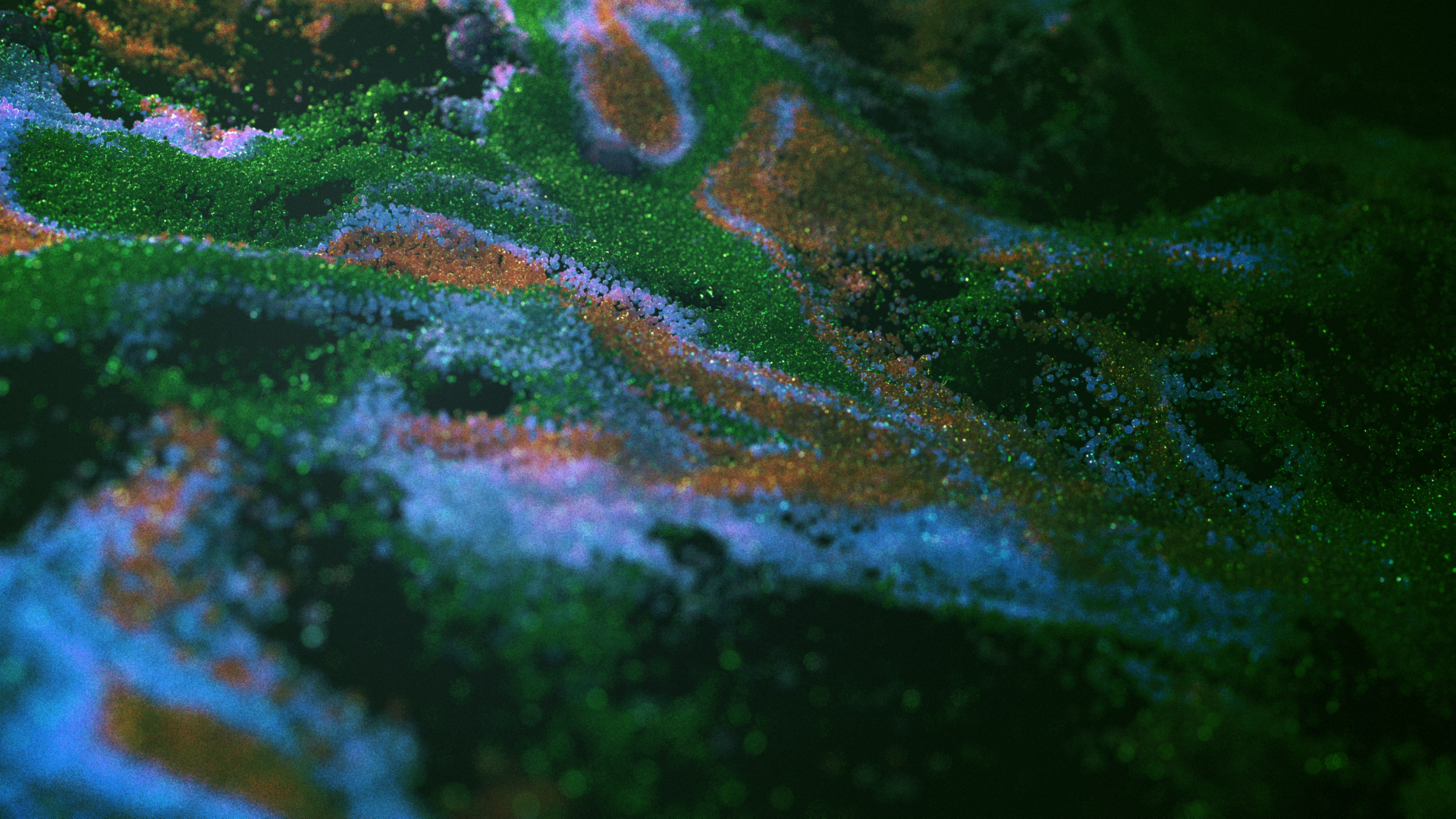 Abstract close-up of colorful particles creating flowing patterns in green, blue, and orange hues on a dark background.